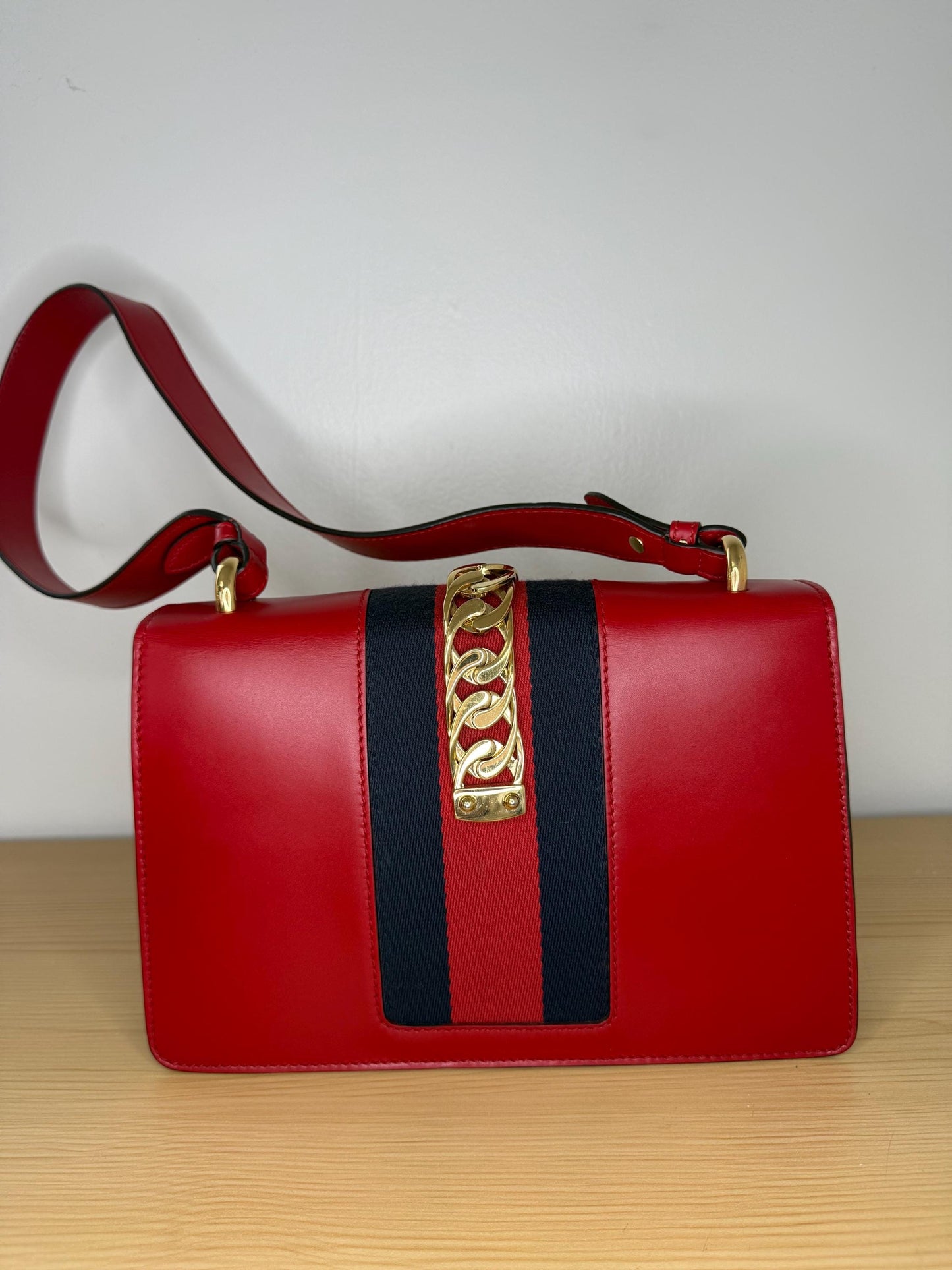AUTHENTIC Gucci Red Leather Sylvie Sholuder Bag with gold-tone chain and buckle hardware.